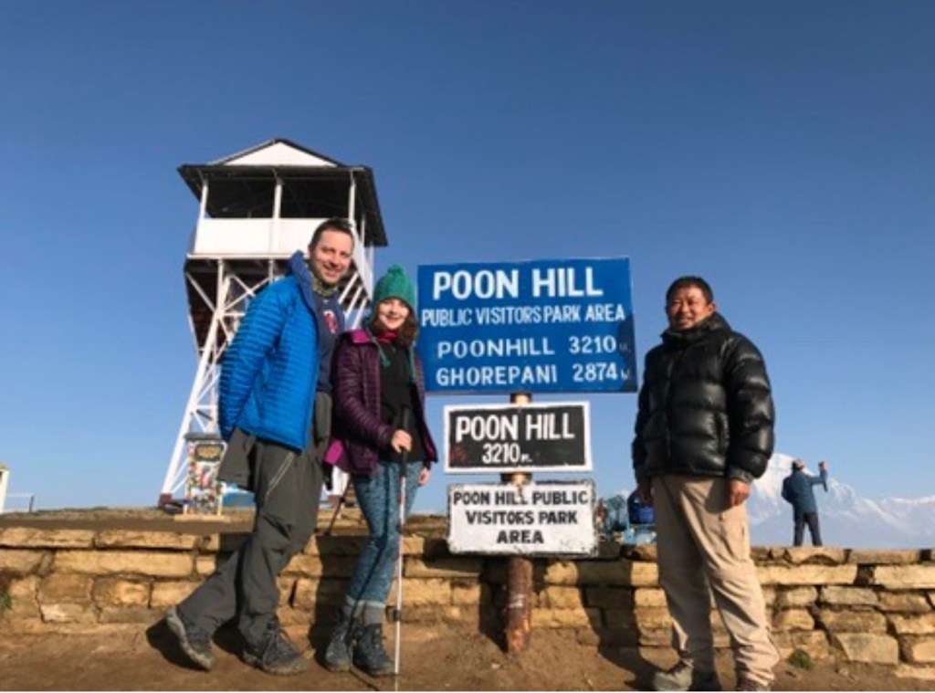 Derik, his daughter Callie, and their Third Rock guide Kewal at the Poon Hill summit sign, 3,210 m, on the Ghorepani Poon Hill trek.