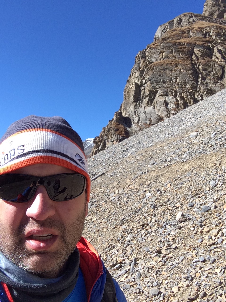 Derik on the Annapurna Circuit with rocky cliffs and blue sky behind.