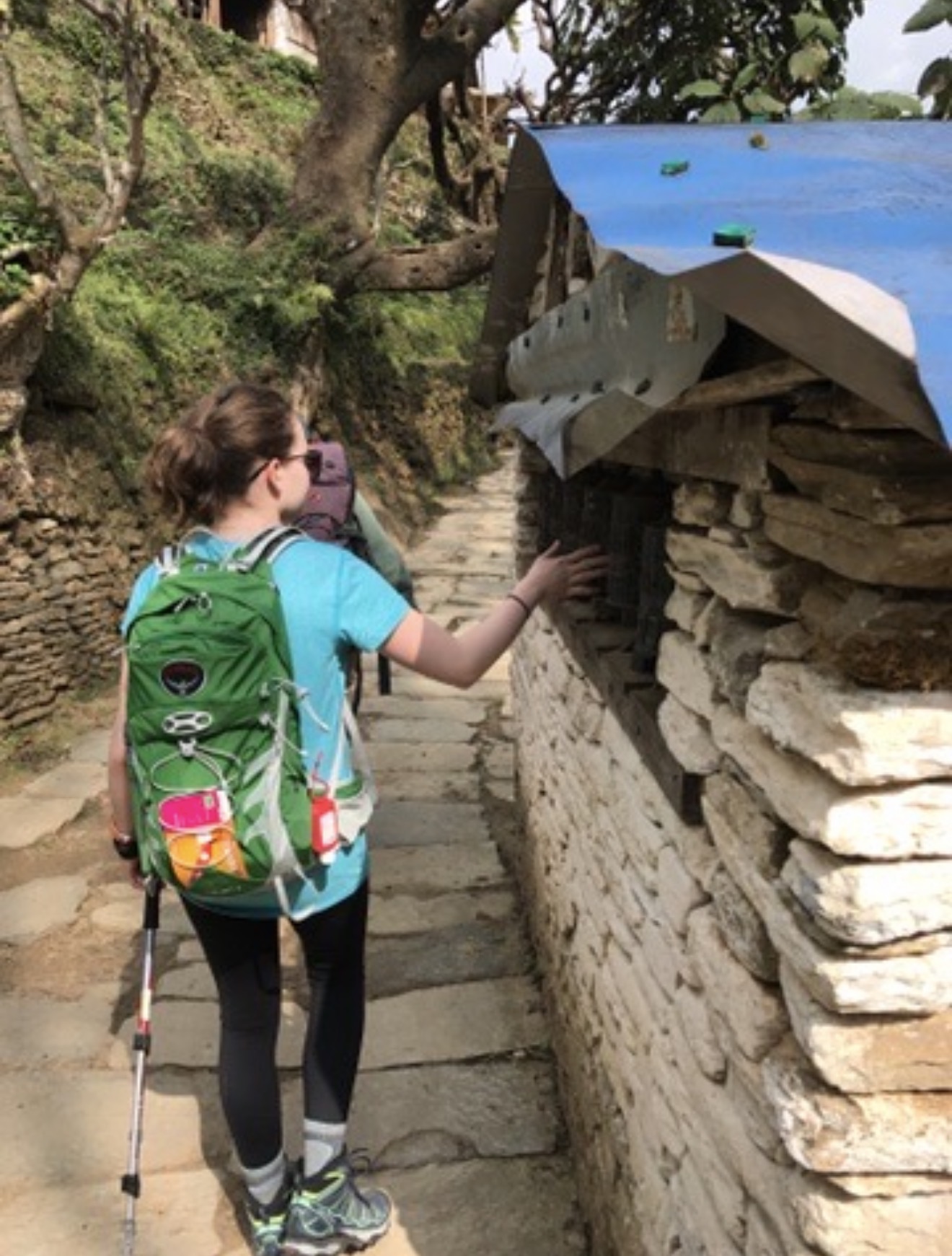 Derik's daughter Callie touching prayer wheels along a Mani-stone wall on the Annapurna trail.