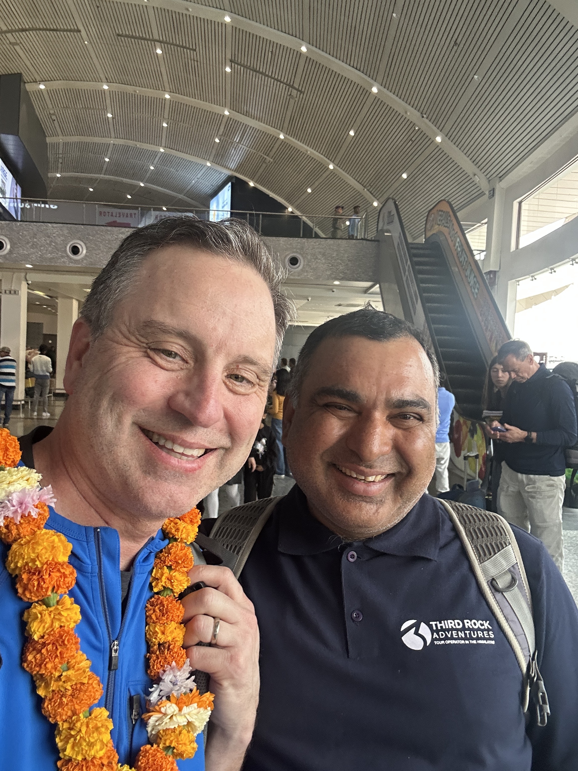 Derik with Rishi, his Third Rock guide, at Tribhuvan airport with marigold welcome garlands.
