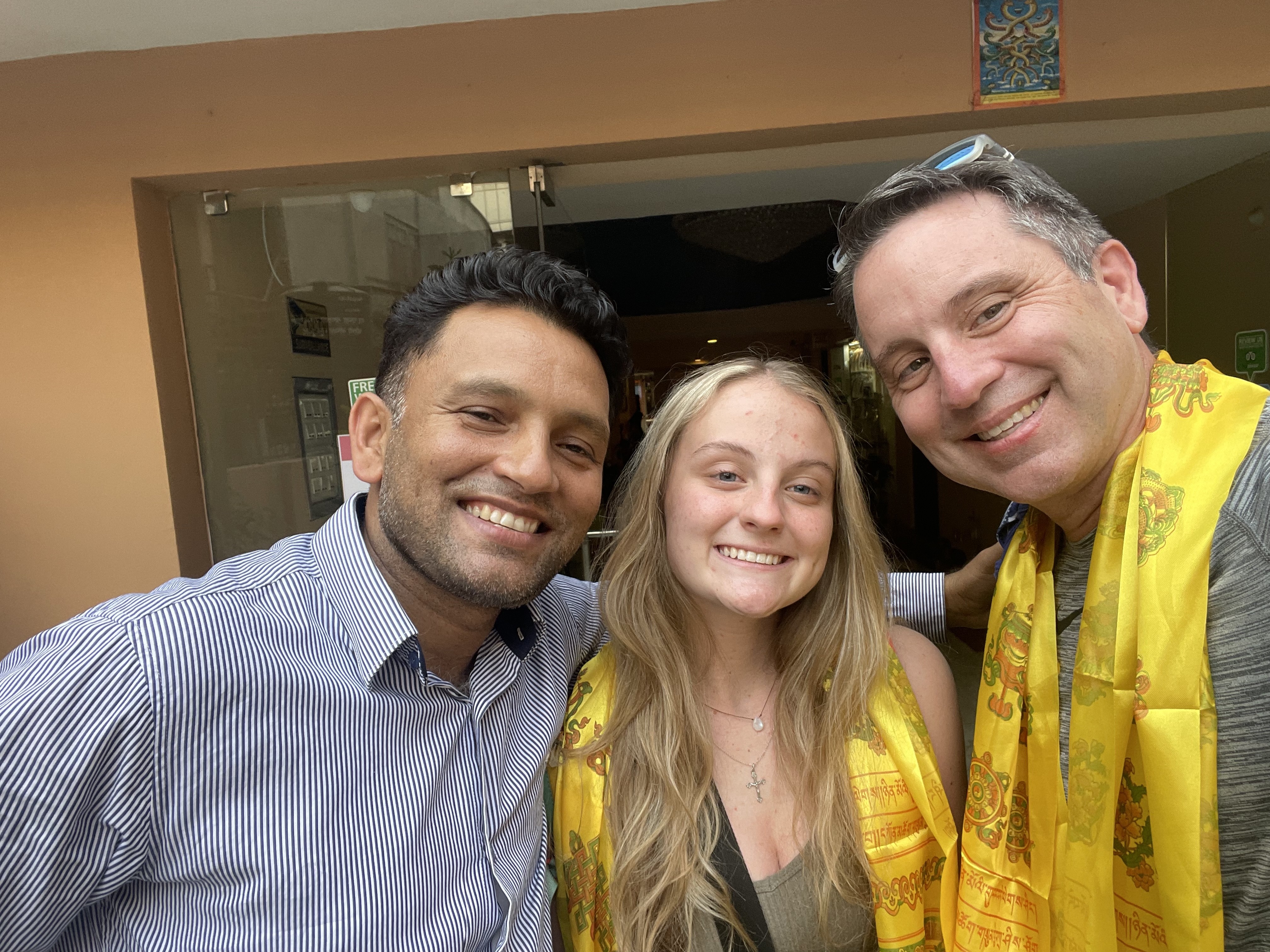 Derik, his daughter Camryn, and Naba of Third Rock Adventures at a Kathmandu hotel with traditional khata scarves.